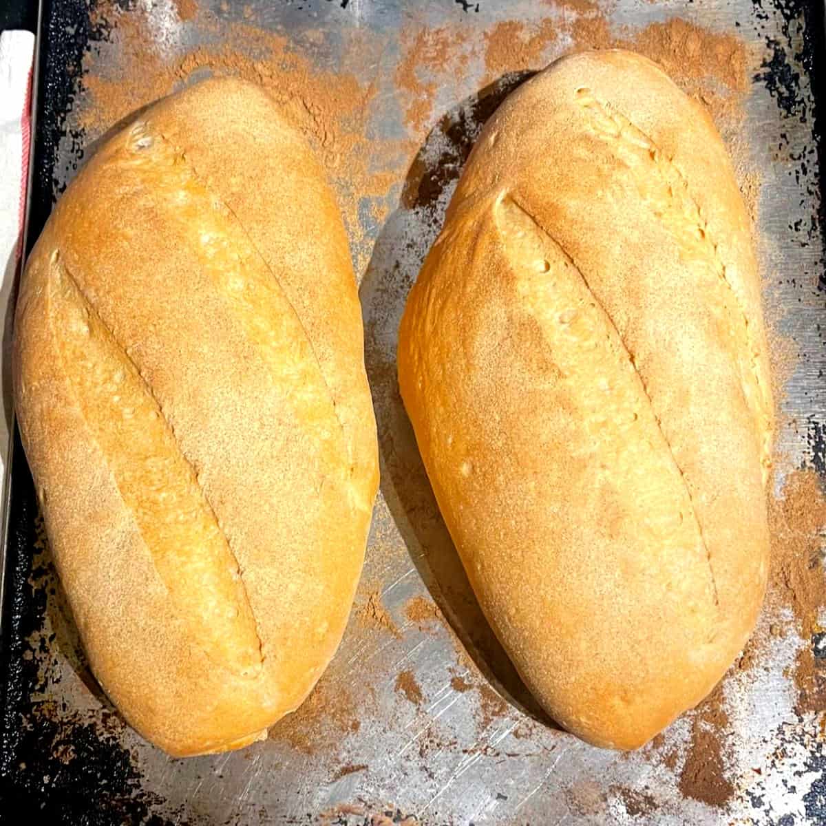 Baked loaves of Italian bread on baking sheet.