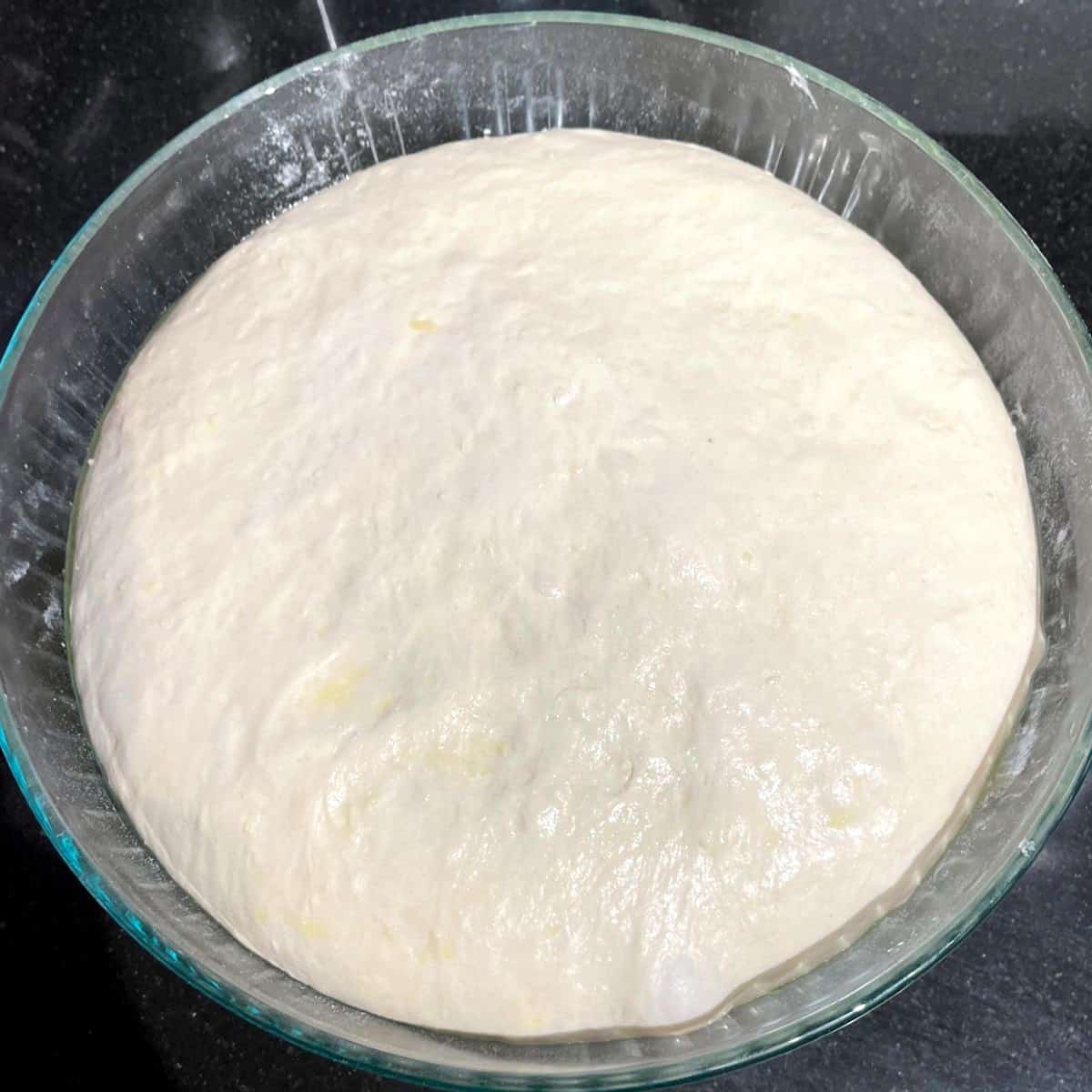 Risen Italian bread dough in bowl.