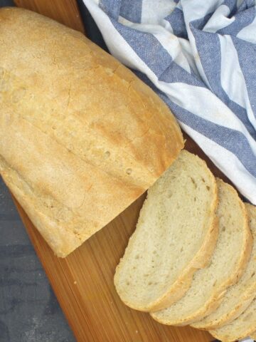 Sliced Italian bread loaf on wooden board.