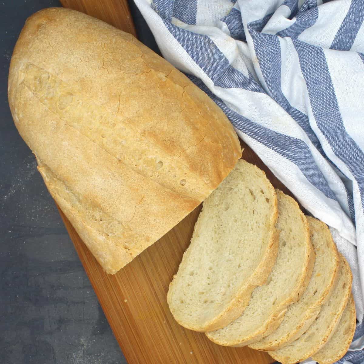 Sliced Italian bread loaf on wooden board.