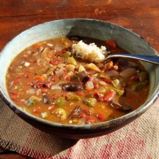 A large bowl of vegan gumbo that's also gluten free, served with brown rice on a wooden table