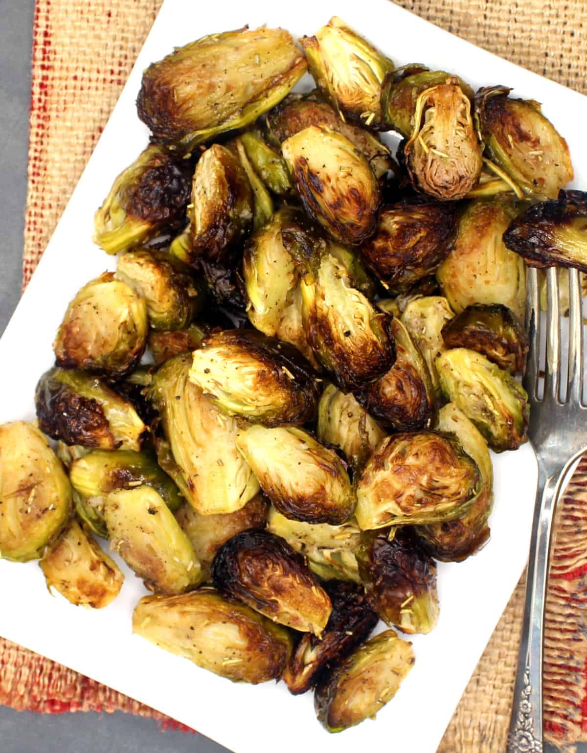 Roasted Brussels sprouts in rectangular white plate with fork.