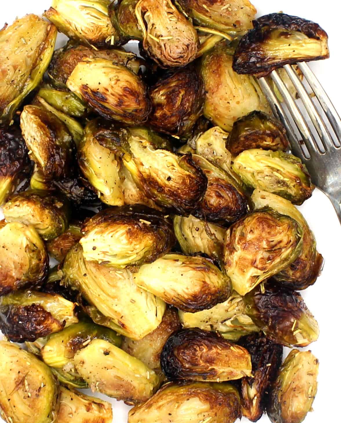 Perfectly roasted Brussels sprouts on white plate with fork.