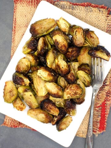 Oven-roasted Brussels sprouts on white plate with fork.