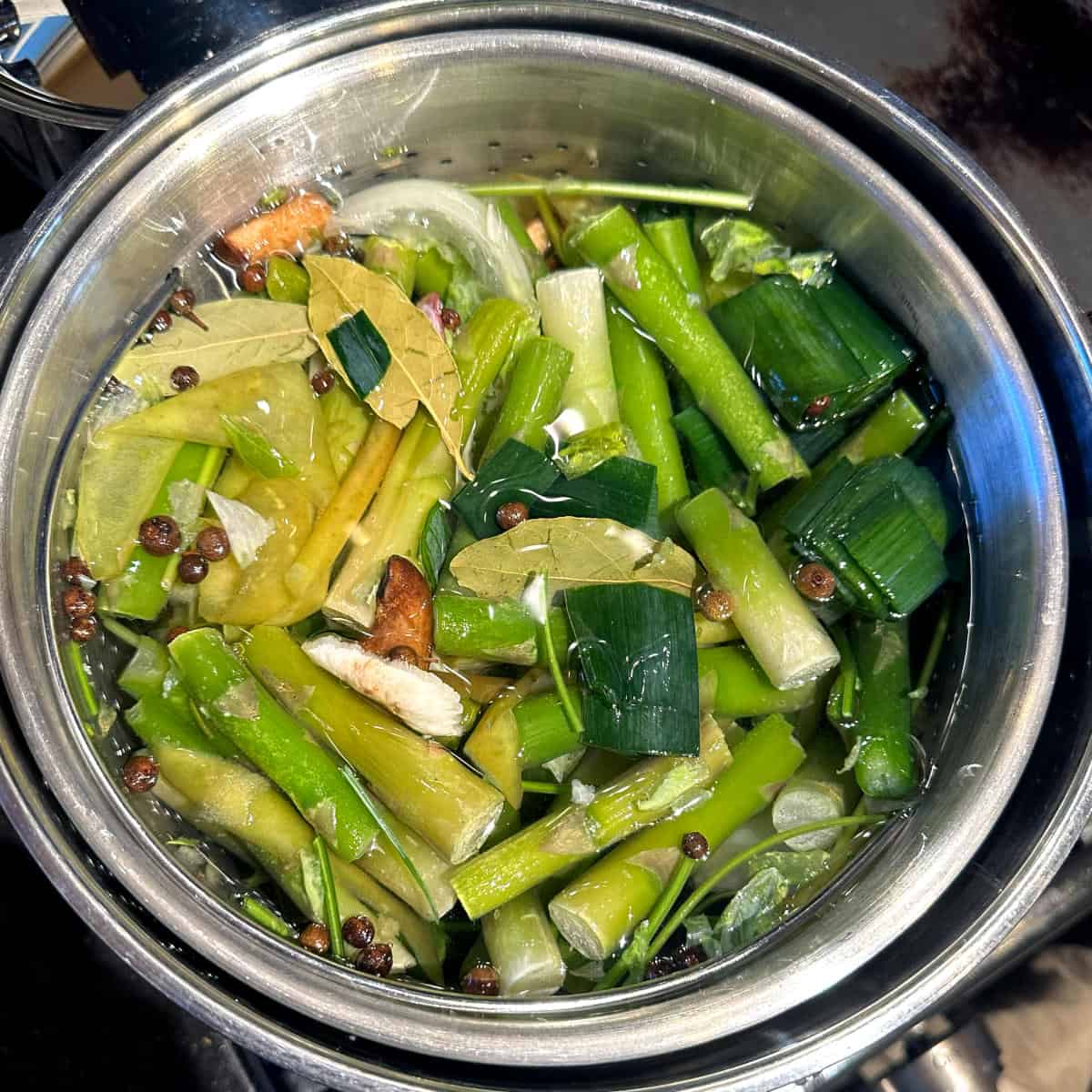 Water added to vegetables and herbs and spices in stockpot.
