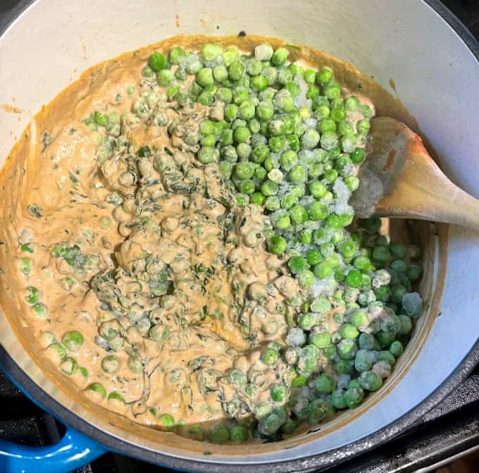 Frozen green peas added to methi and cashew sauce in sauce pan.