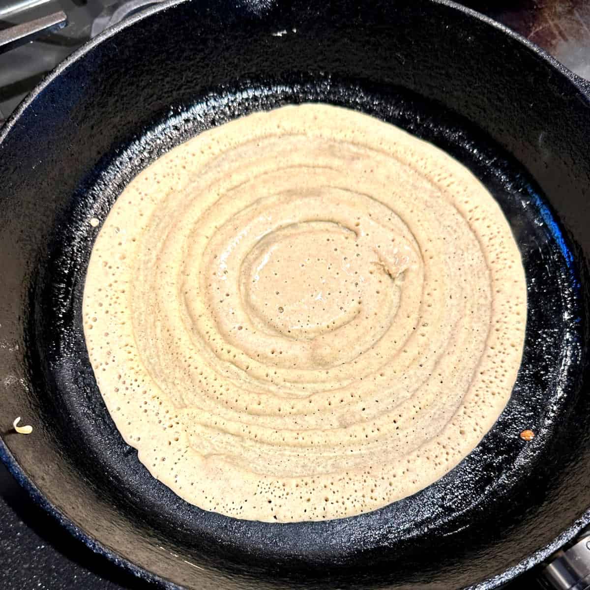 Dosa frying on skillet.