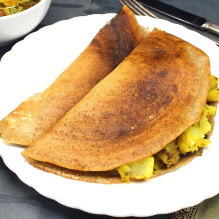Instant masala dosa with potato stuffing in white plate.