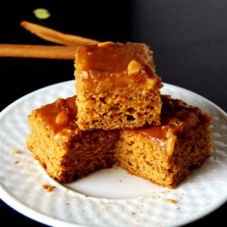 Sweet potato bars stacked in white plate with cinnamon sticks and cardamom in background.