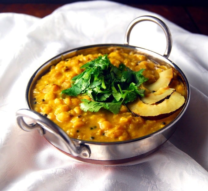 Cholar dal in a steel karahi slices of dry coconut and cilantro.