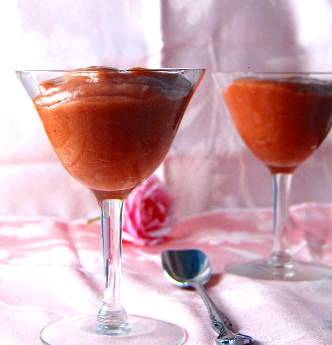 Two cocktail glasses with Rhubarb Mousse on a pink silk fabric with a spoon and a pink rose in teh background