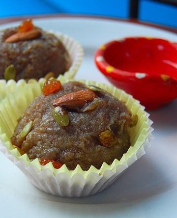Almond halwa in paper cups with an earthen diya on the side.