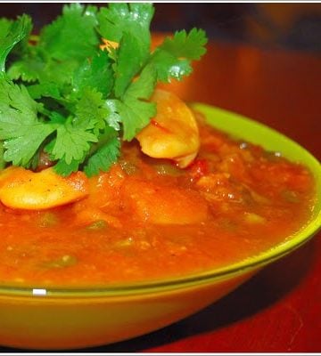 Spicy fava bean and eggplant stew in bowl with cilantro garnish.