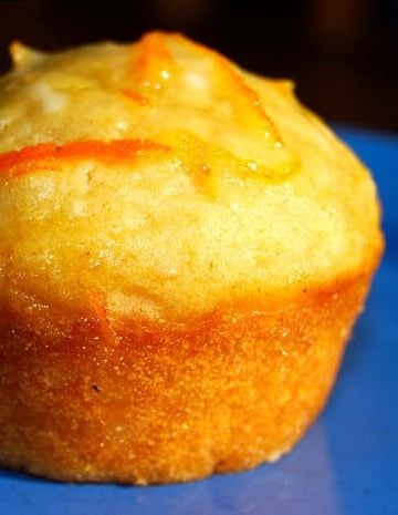 A vegan coconut muffin with orange glaze on blue plate.