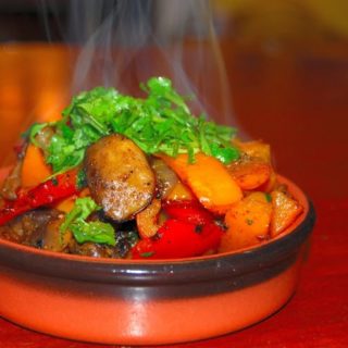 Pepper mushroom stir fry with cilantro garnish in earthen bowl.