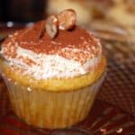 Vegan orange cupcakes with orange buttercream frosting and a dusting of cocoa. Almonds are used for garnish on top.