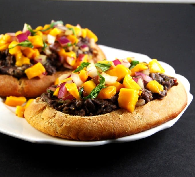 Vegan Molletes with refried beans and mango basil salsa on a white plate.