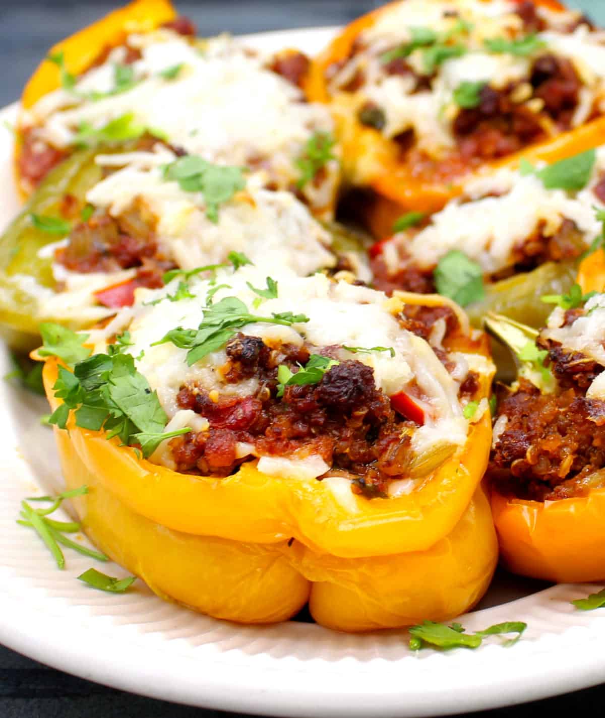 Stuffed bell peppers with parsley garnish on oval plate.