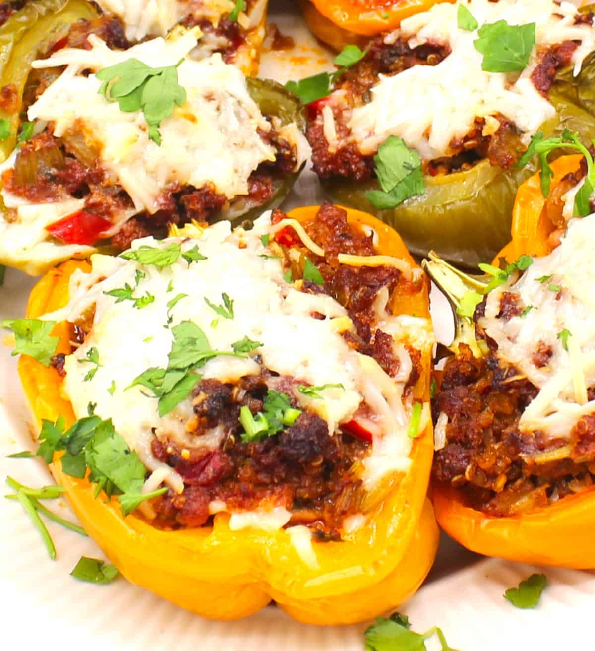 Stuffed bell peppers with vegan cheese and parsley garnish.