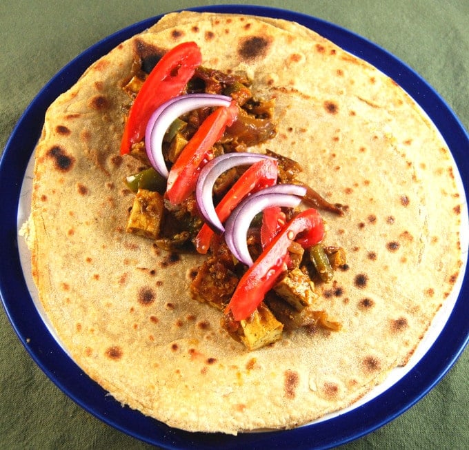 Vegan Kati Roll, open, with tofu filling, bell peppers and onions on a blue and white ceramic plate.