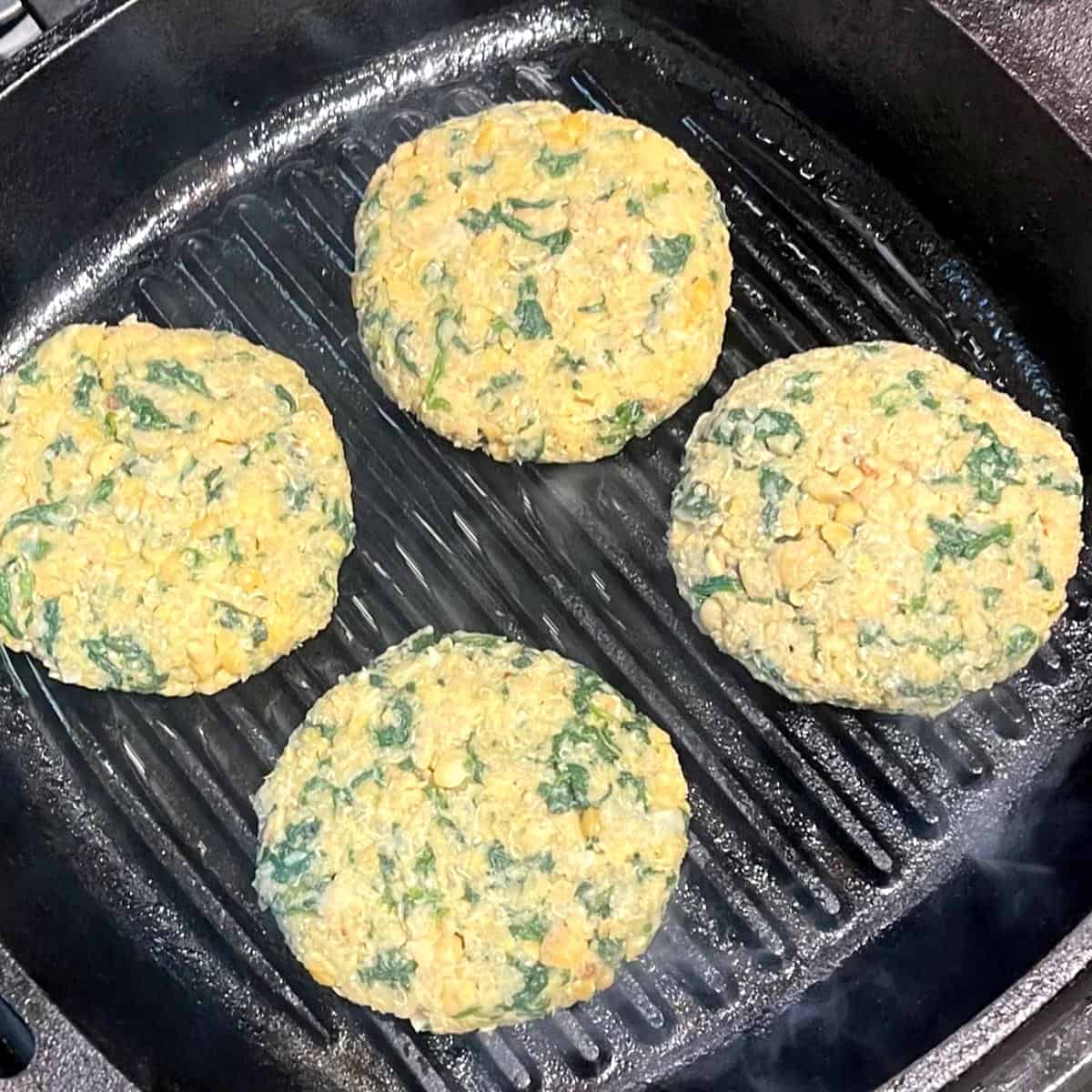 Chickpea quinoa burger patties on a grill pan.