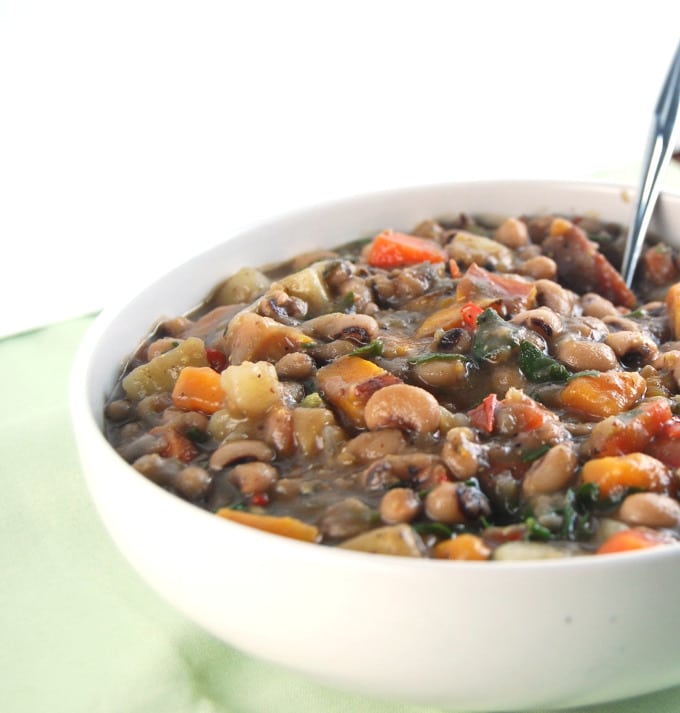 Caribbean Black Eyed Peas Stew in white bowl with spoon.