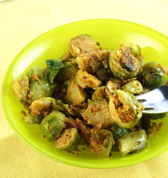 Pan-roasted brussels sprouts in green bowl with a fork.