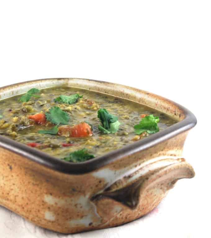 A brown clay bowl with methi dal in it.