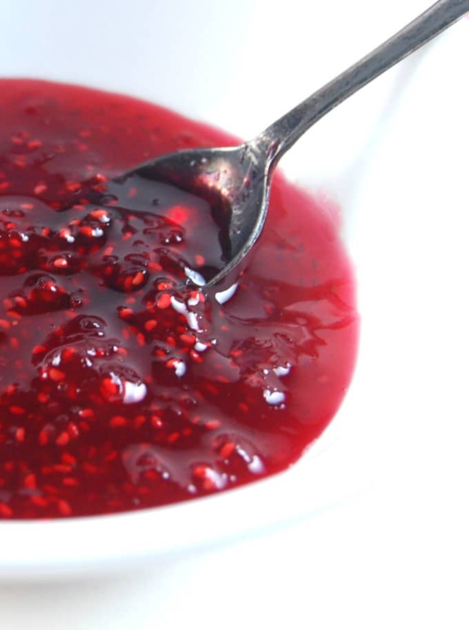 Closeup of raspberry jam in a bowl with spoon.