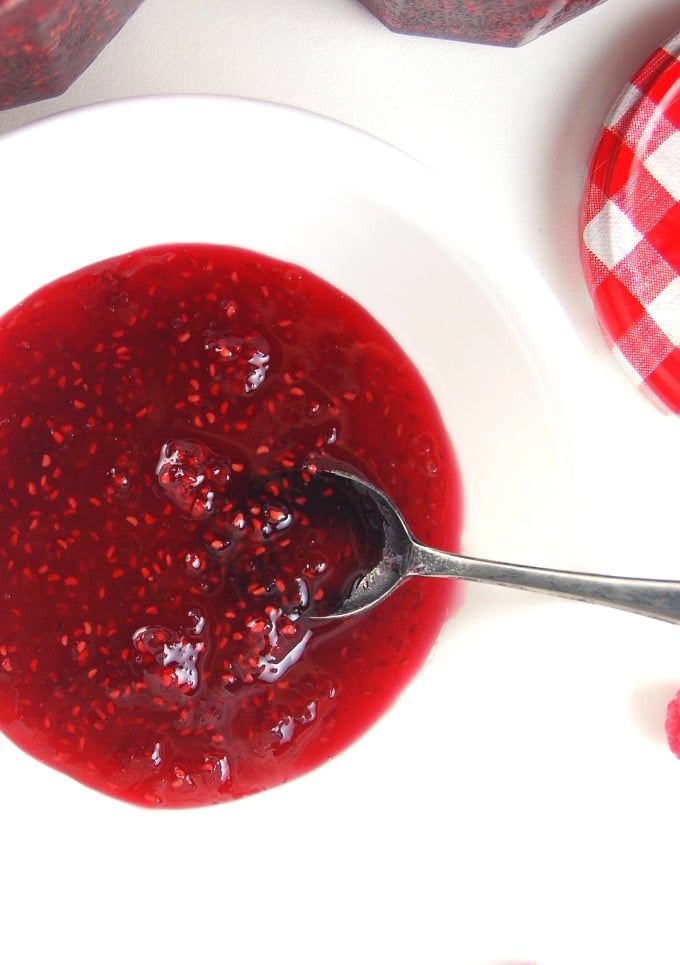 Raspberry Jam in a white bowl with spoon.