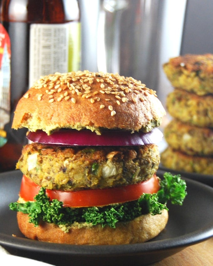 Closeup of a single vegan sprouted mung bean burger with kale, tomato, onion.