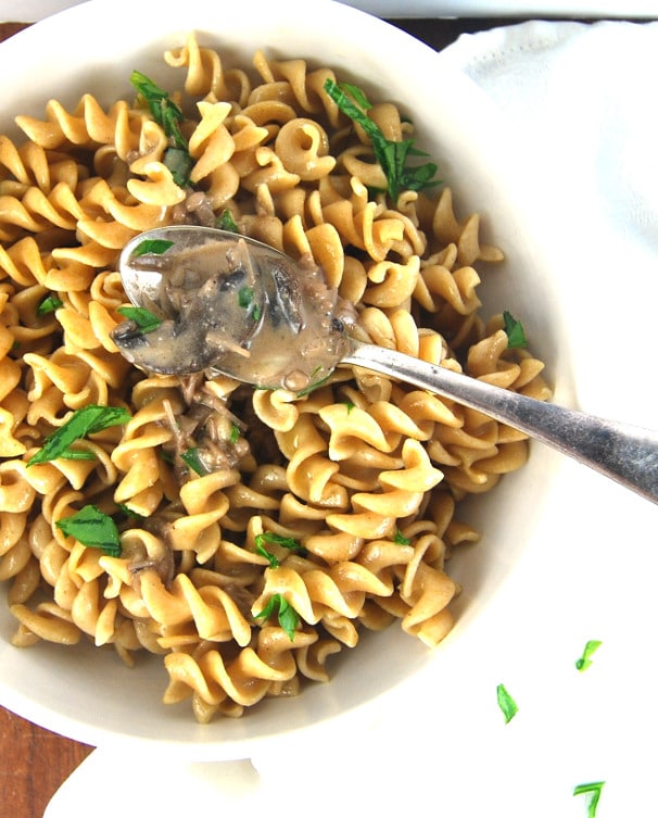 Corkscrew pasta mixed with vegan mushroom ragout in a bowl with spoon.