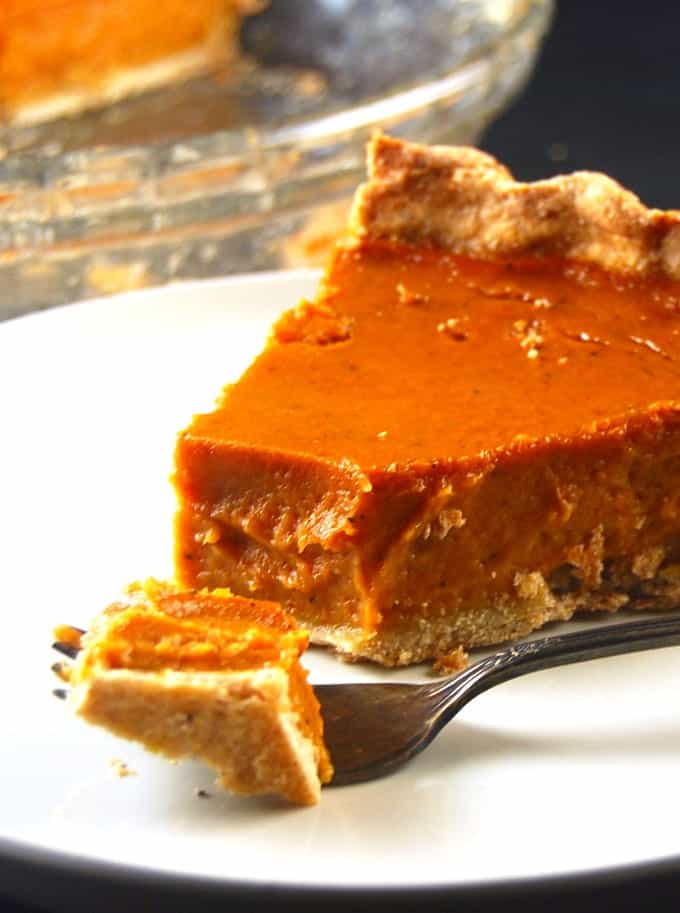 Photo of a slice of vegan pumpkin pie with a wholegrain crust.