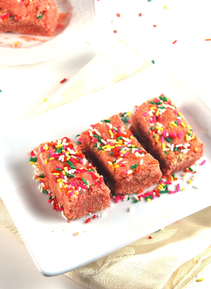 Pink Lemonade Cookie Bars decorated with sprinkles on a white plate.