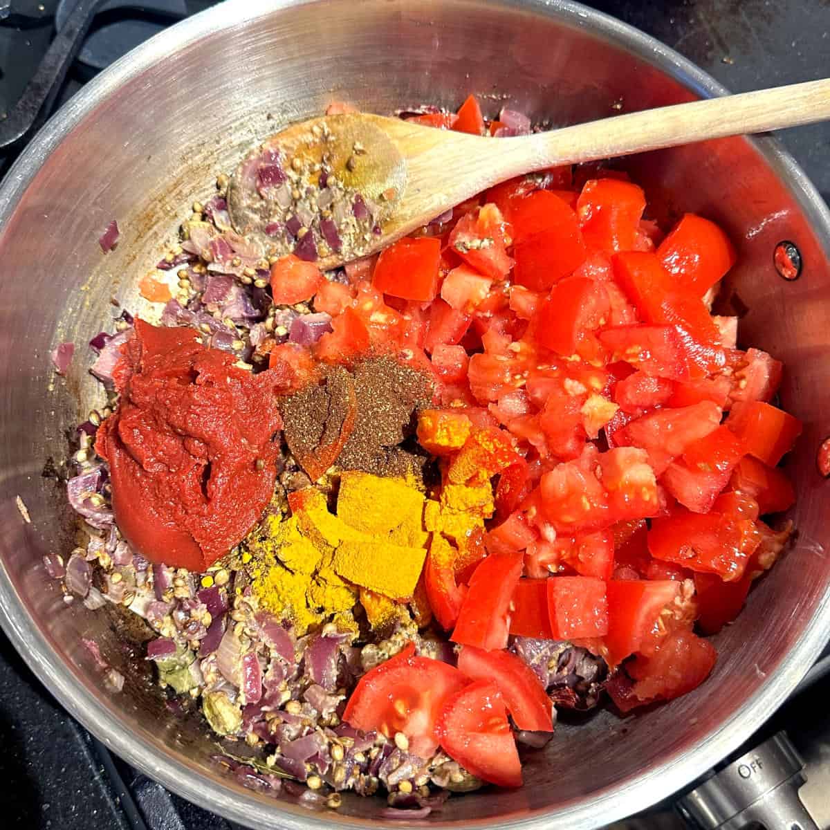 Tomatoes, tomato paste and spices added to onions.