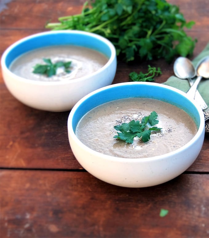 Front photo of Smoky Roasted Eggplant Soup with Za'atar in two blue and white bowls with parsley and spoons.