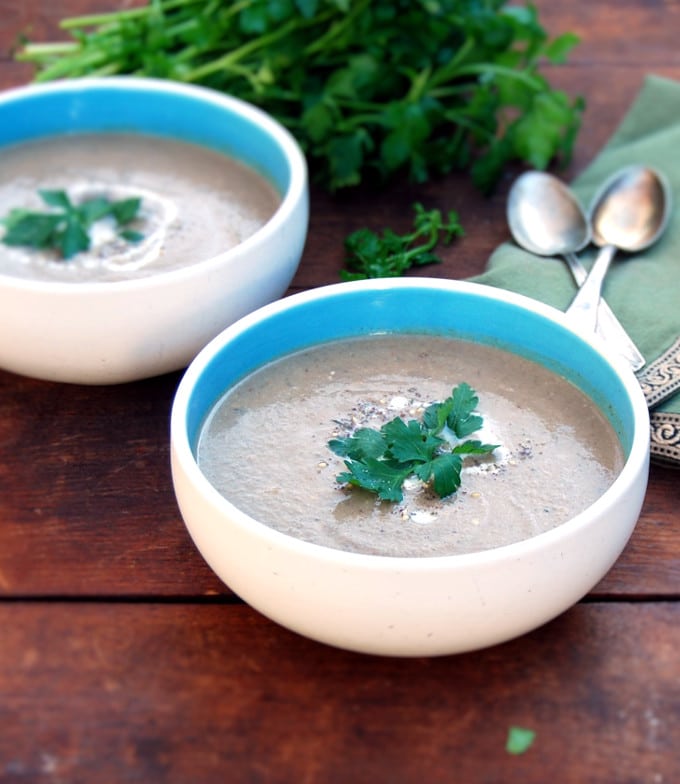 Smoky Roasted Eggplant Soup with Za'atar in two bowls with parsley, spoons and a napkin.
