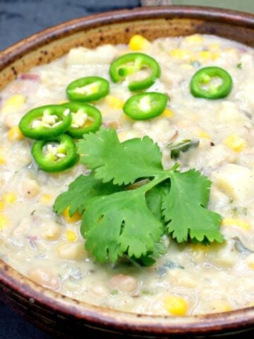 Vegan white bean chili in bowl with cilantro and jalapeno peppers.