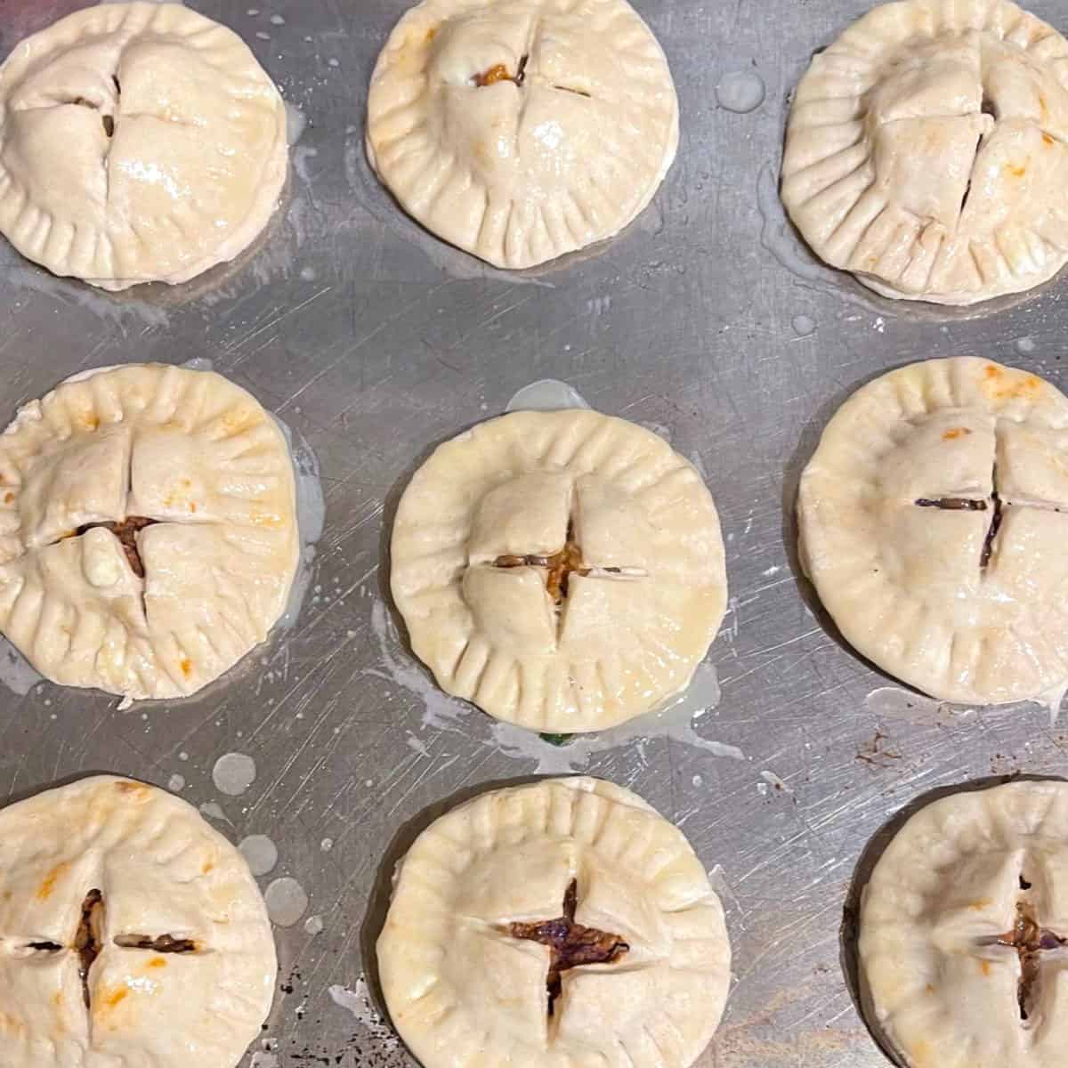 Irish hand pies ready for baking on baking sheet.