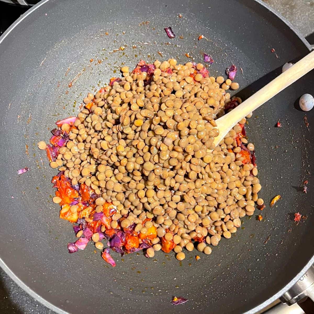 Lentils added to tomato, potato and cabbage filling in wok.