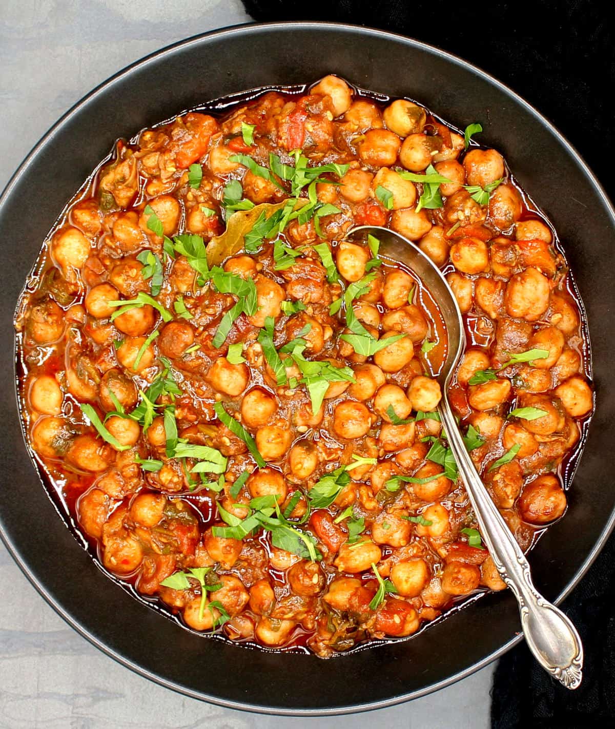 Lebanese chickpea stew in black bowl with spoon.