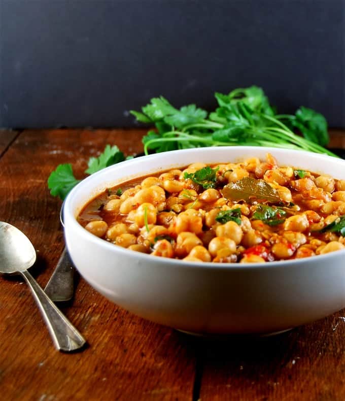Lebanese Chickpea Stew in a white bowl with spoons.