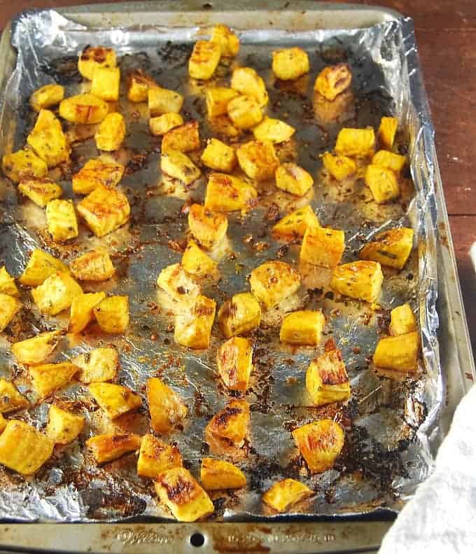 Roasted golden beet cubes on a tinfoil-lined baking sheet.