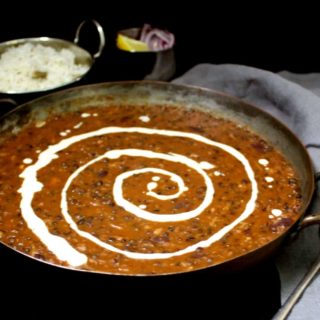 Front partial shot of vegan dal makhni or dahl makhani with a swirl of cashew cream and rice in background