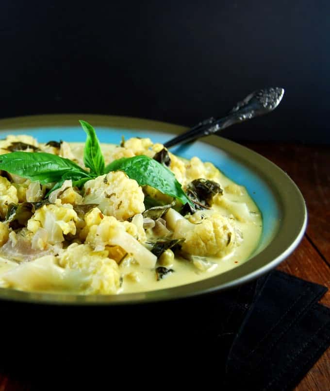 Front partial photo of creamy Cauliflower Curry with Basil in blue and brown bowl with spoon.