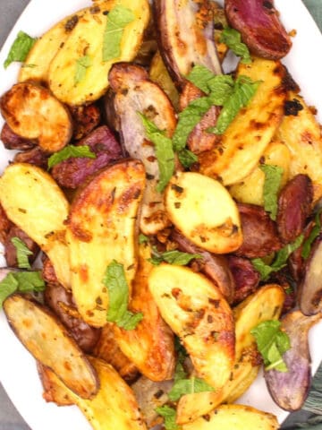Roasted fingerling potatoes with rosemary and garlic in white plate.