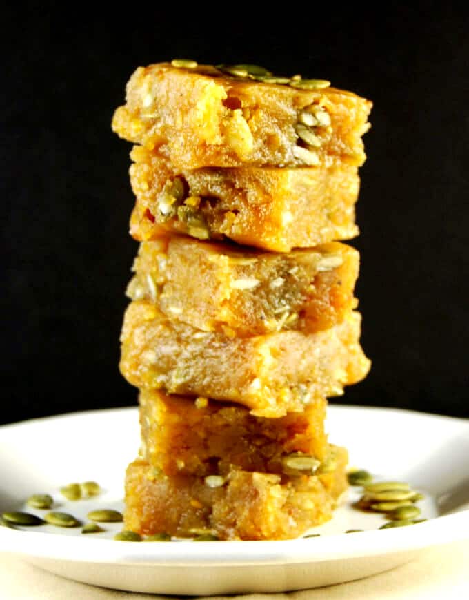 Vegan Chana Dal Burfi, stacked on a white plate with pumpkin seeds.