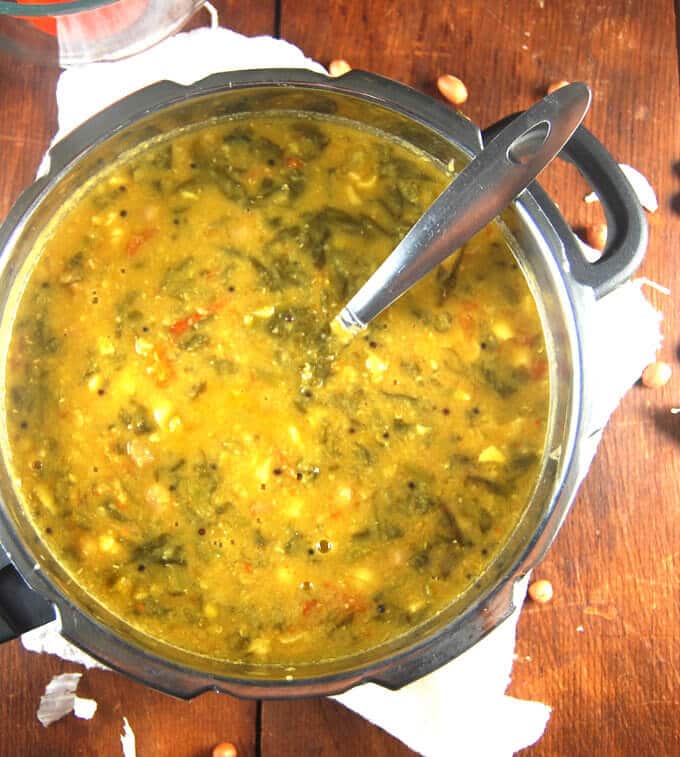 Garlicky Spinach Dal in pressure cooker with ladle.