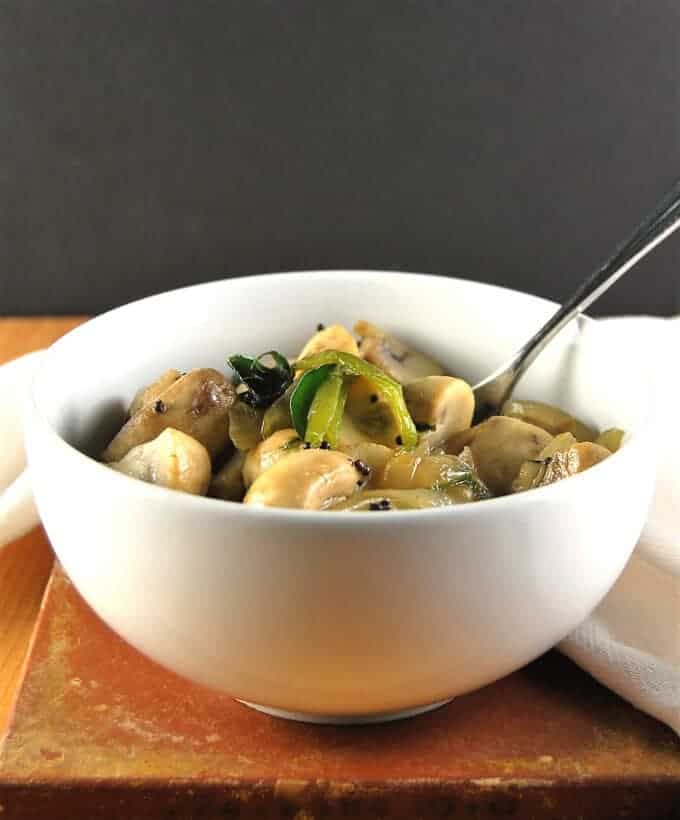15-Minute Stir-Fried Mushrooms in white bowl with fork on a wooden table.