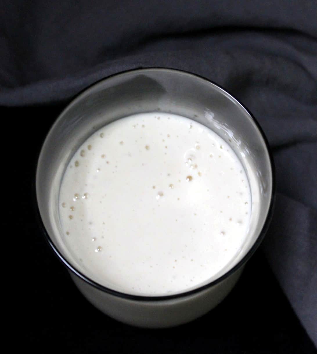Mature Sourdough Starter with bubbles in a glass jar on a black background